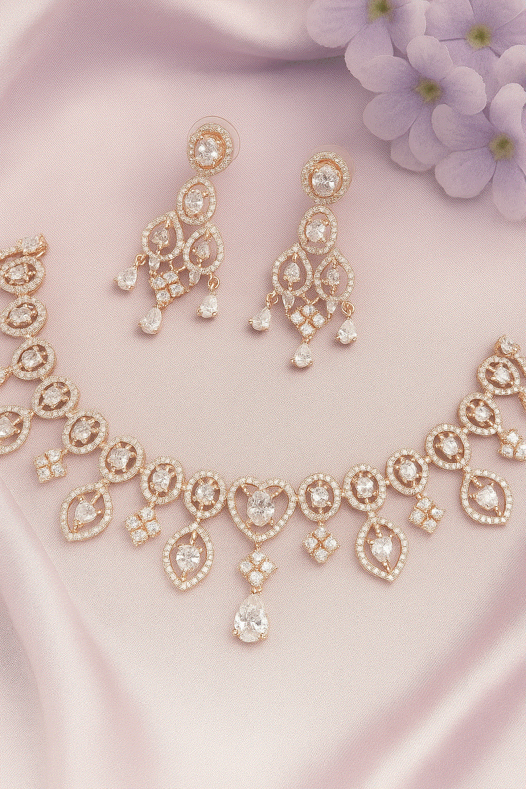 Luxury CZ Intimate Jewelry Set with gold-plated heart and teardrop cubic zirconia necklace and chandelier earrings on pink fabric background