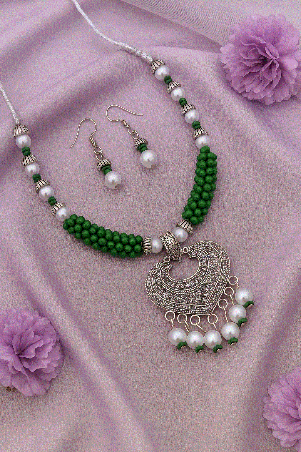 Handcrafted Heart Mandala oxidized silver heart pendant necklace with green beads and faux pearls, matching earrings on lavender fabric background