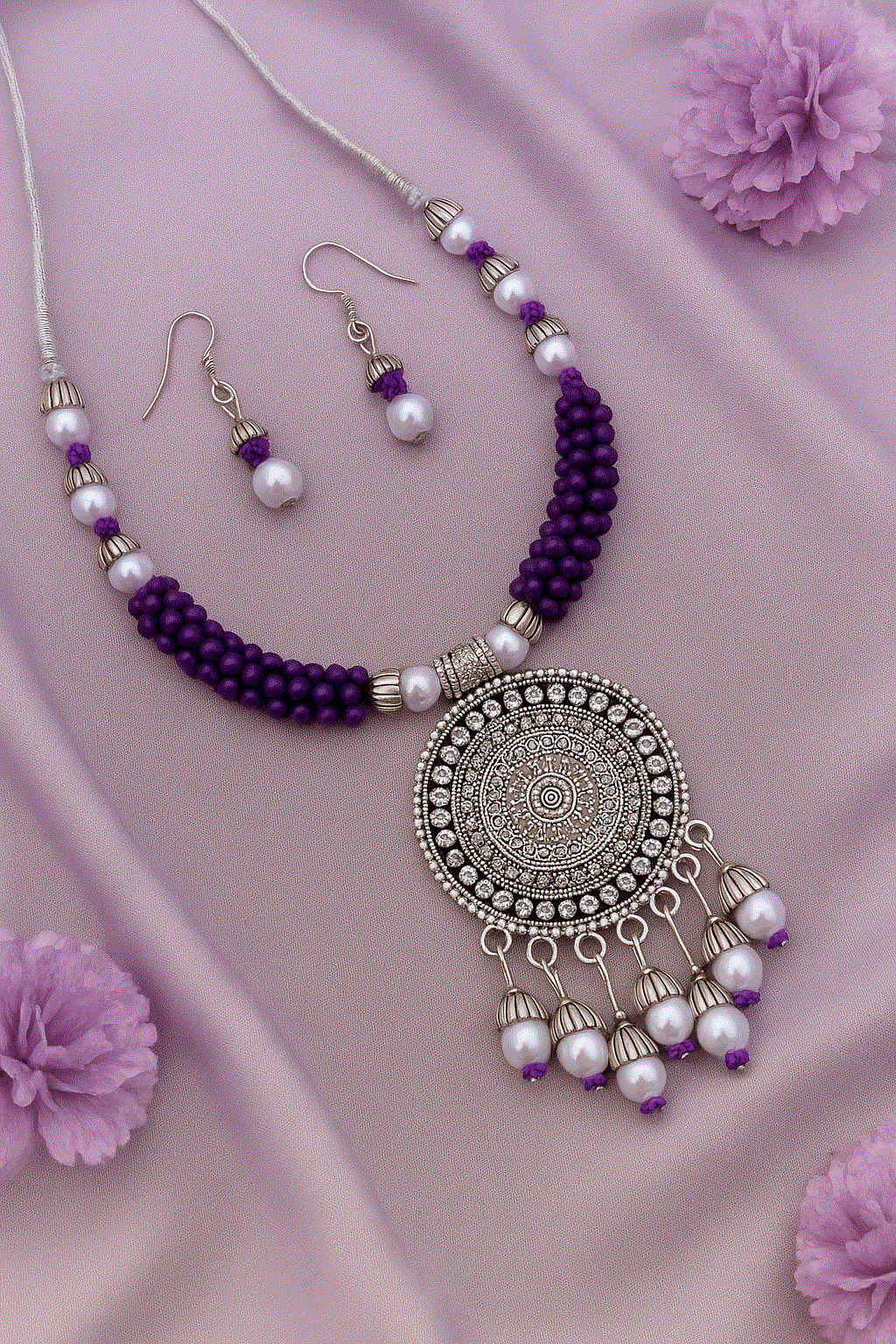Handcrafted Mandala Intimate Jewelry Set with oxidized silver look, tribal purple beads, and faux pearl necklace with matching earrings on pink fabric.
