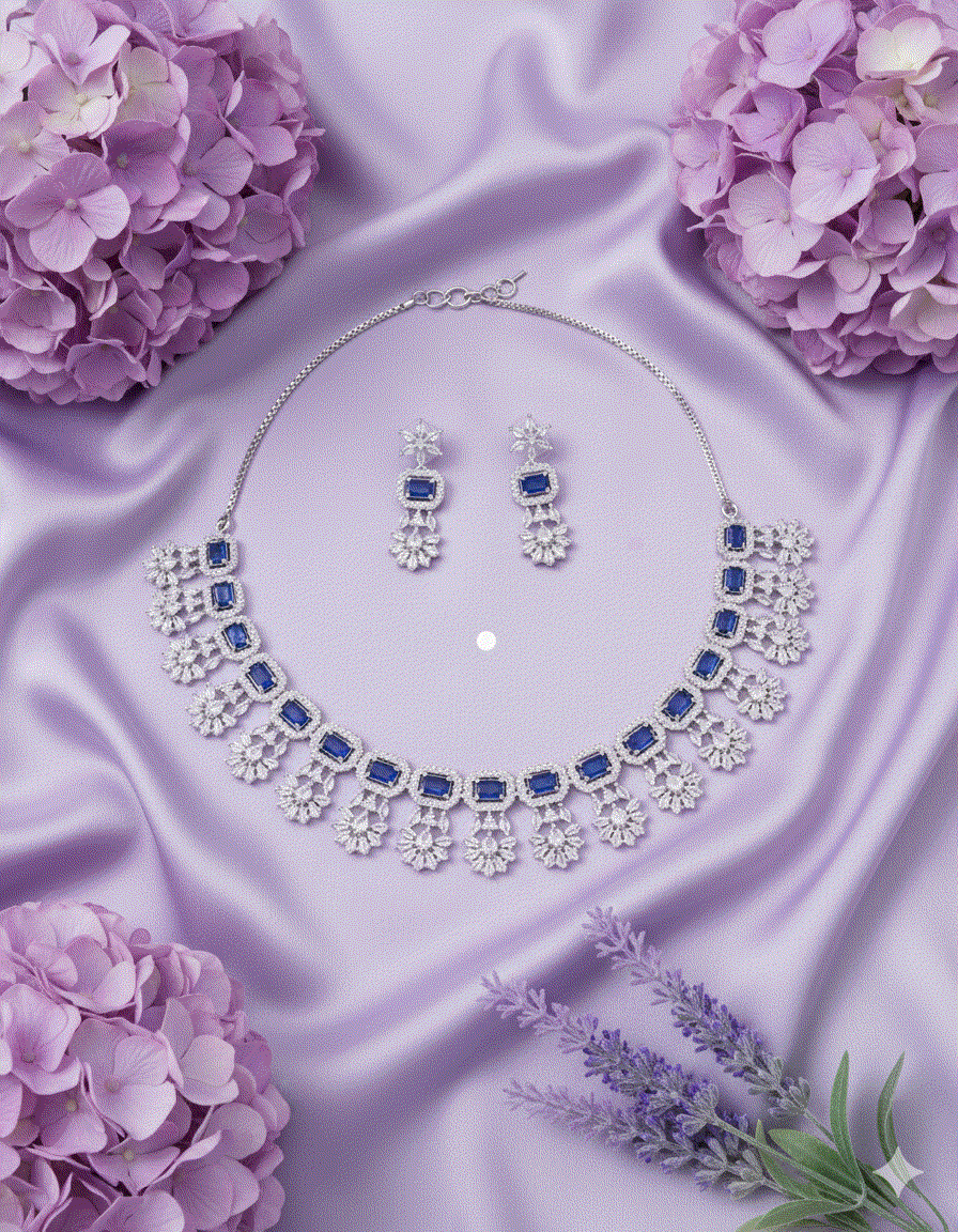 Rhodium plated intimate jewelry set with sapphire blue teardrop CZ choker and matching drop earrings on purple satin background