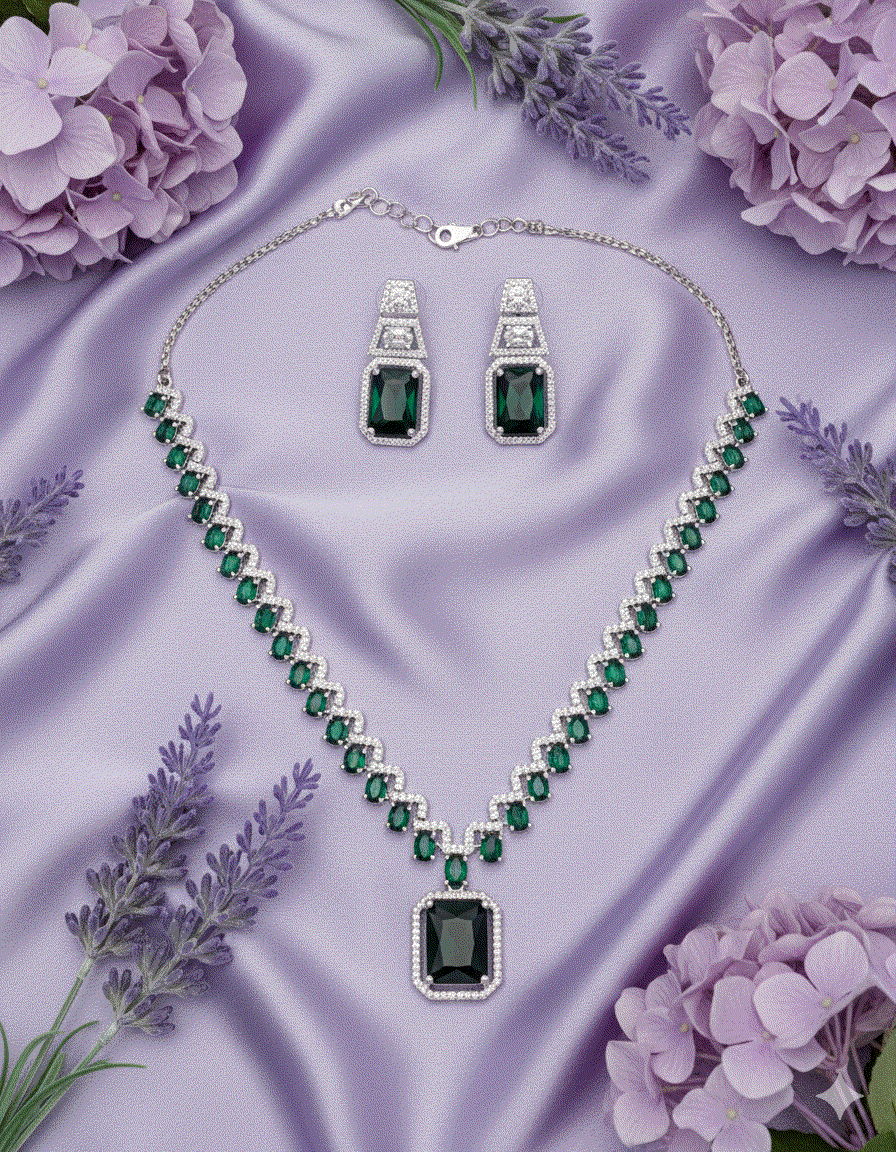 Intimate Jewelry set with emerald green cubic zirconia collar necklace and matching drop earrings on purple satin background