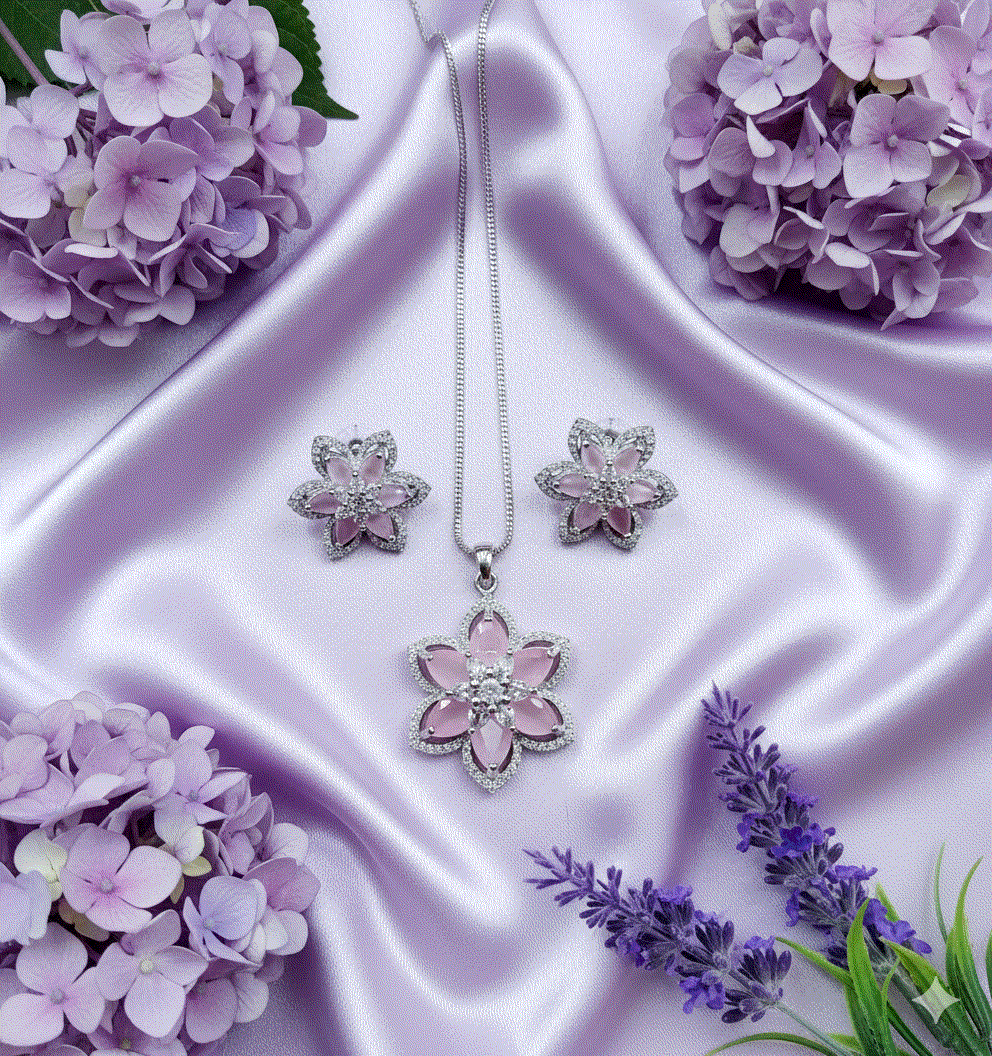 Intimate Jewelry clear CZ floral pendant and earrings set on rhodium plated chain displayed on lavender satin with purple flowers
