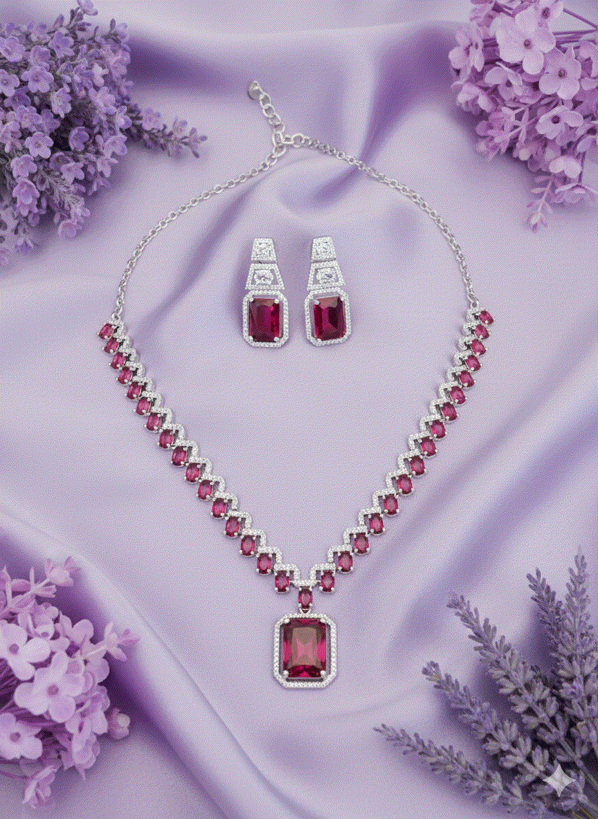 Luxury intimate jewelry set with emerald-cut red stones necklace and matching earrings on purple fabric background
