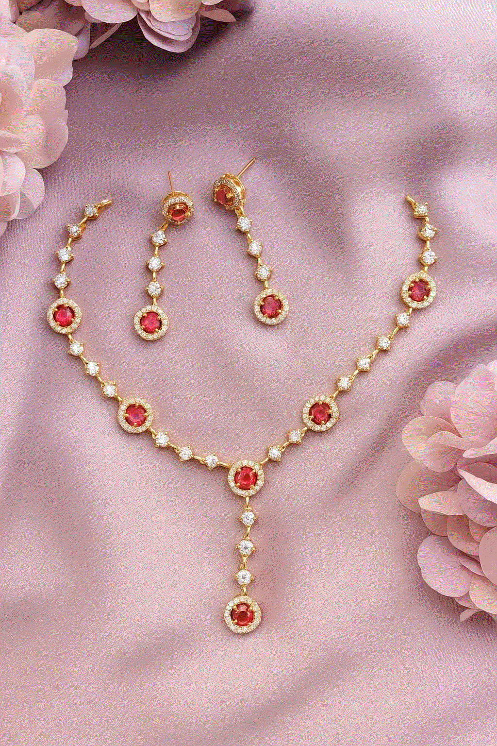 Gold-plated ruby CZ Y-necklace and earrings set on pink fabric background