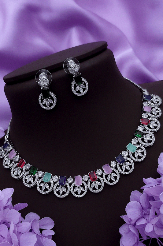 Vibrant multi-color CZ diamond necklace and stud earrings set with silver-toned floral design on black display bust against purple satin background