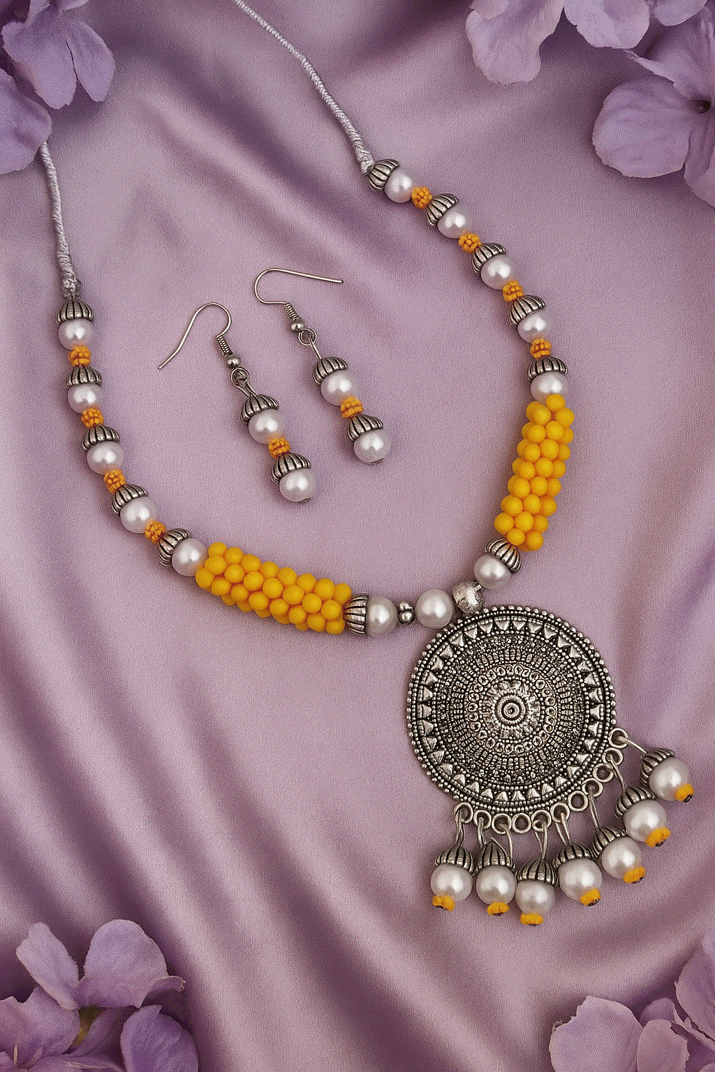 Vibrant yellow bead and faux pearl oxidized silver necklace with matching drop earrings on purple silk background