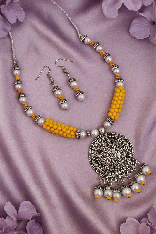 Vibrant yellow bead and faux pearl oxidized silver necklace with matching drop earrings on purple silk background