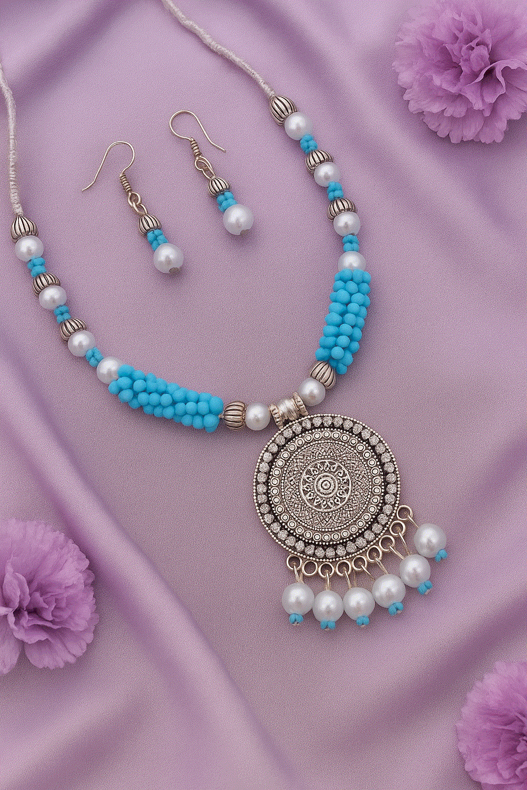 Bohemian Mandala Intimate Jewelry Set with tribal blue beads, faux pearls, oxidized silver pendant, and matching earrings on purple fabric background