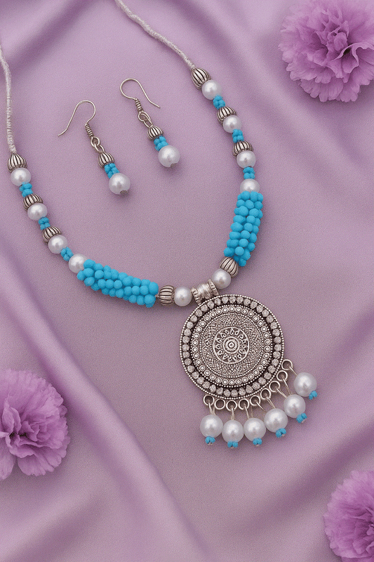 Bohemian Mandala Intimate Jewelry Set with tribal blue beads, faux pearls, oxidized silver pendant, and matching earrings on purple fabric background