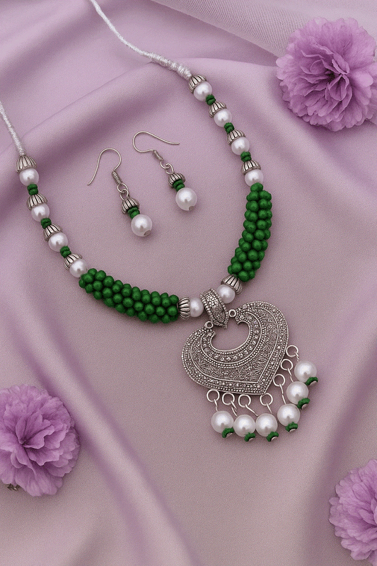 Handcrafted Heart Mandala oxidized silver heart pendant necklace with green beads and faux pearls, matching earrings on lavender fabric background