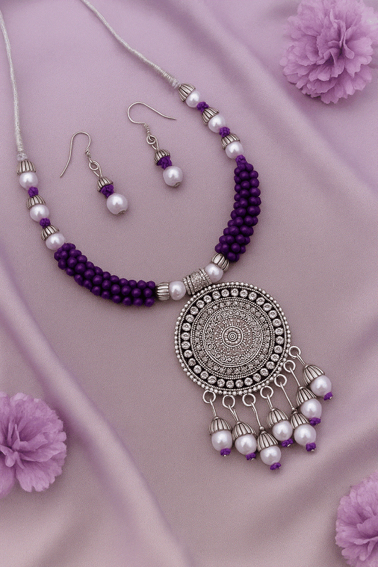 Handcrafted Mandala Intimate Jewelry Set with oxidized silver look, tribal purple beads, and faux pearl necklace with matching earrings on pink fabric.