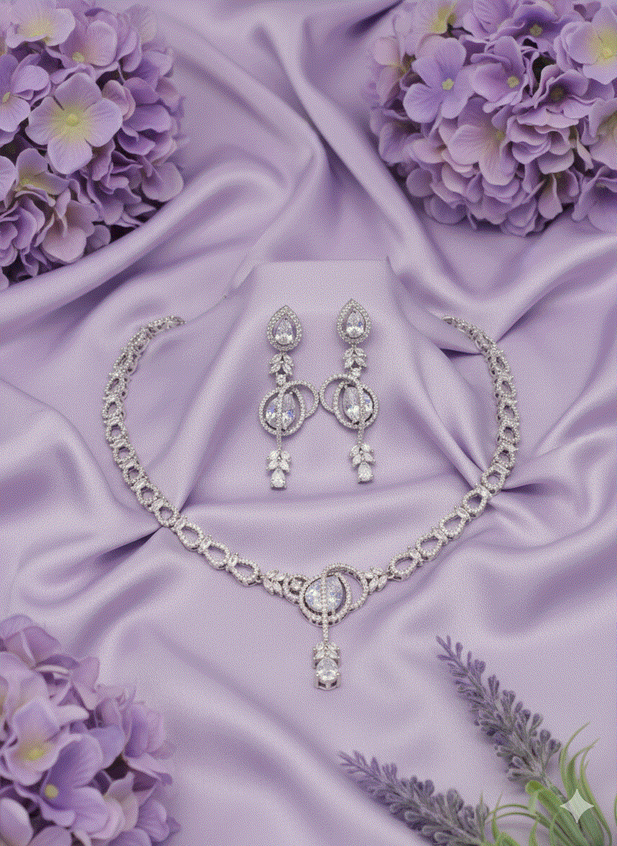 Intimate Jewelry necklace set with rhodium-plated oval and marquise CZ links, round solitaire pendant, and teardrop earrings on lavender silk background.