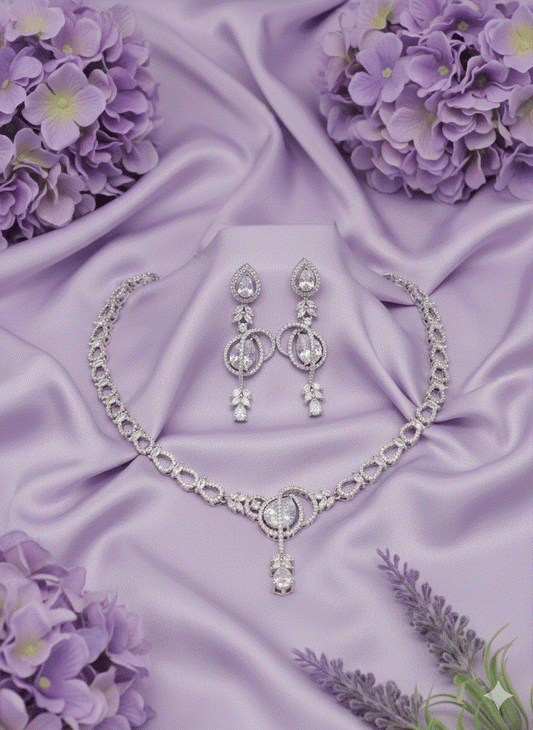 Intimate Jewelry necklace set with rhodium-plated oval and marquise CZ links, round solitaire pendant, and teardrop earrings on lavender silk background.