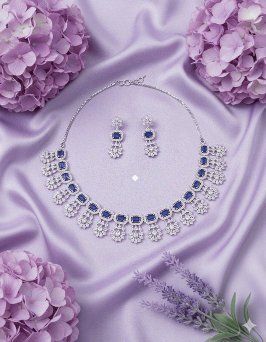 Rhodium plated intimate jewelry set with sapphire blue teardrop CZ choker and matching drop earrings on purple satin background