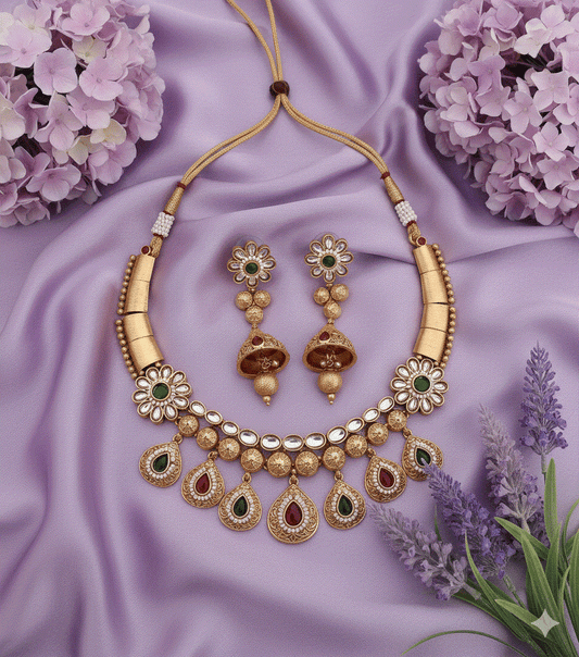 Traditional gold plated stone studded and beaded choker necklace set with kundan-look ruby and emerald stones and matching earrings on purple fabric background