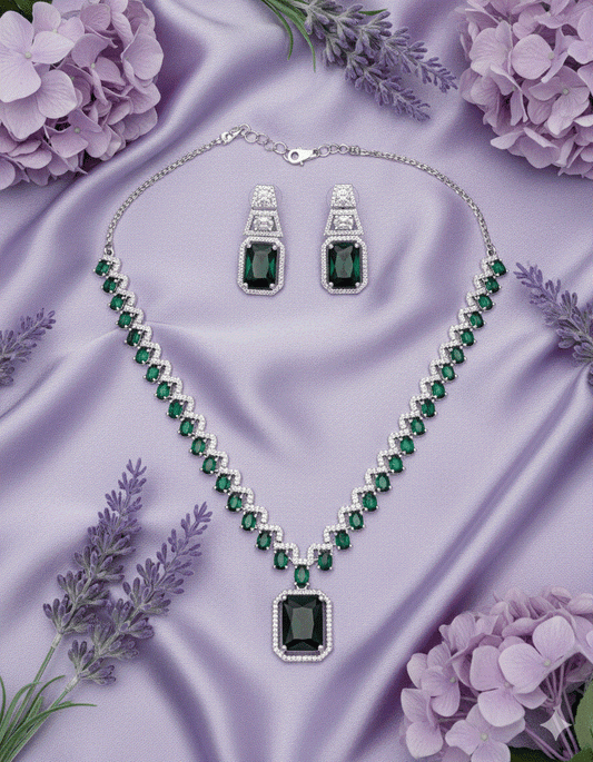 Intimate Jewelry set with emerald green cubic zirconia collar necklace and matching drop earrings on purple satin background