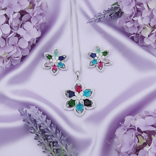 Vibrant multi-color floral pendant and stud earrings set with marquise-cut CZ stones and rhodium plating on lavender silk background.