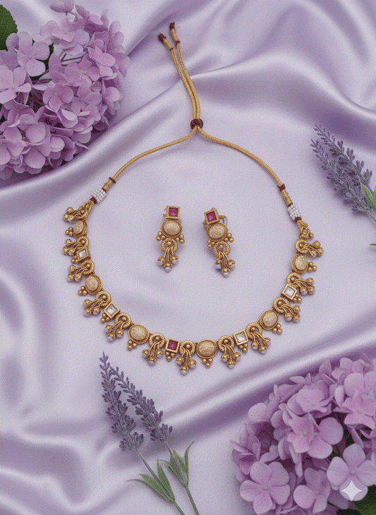 Heritage intimate jewelry matte gold plated kundan-look choker necklace set with ruby and beige enamel stones and matching earrings on satin background