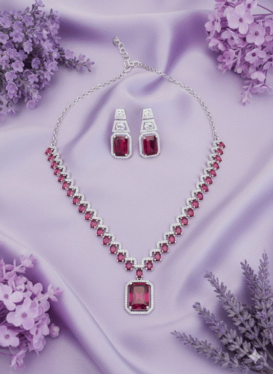 Luxury intimate jewelry set with emerald-cut red stones necklace and matching earrings on purple fabric background
