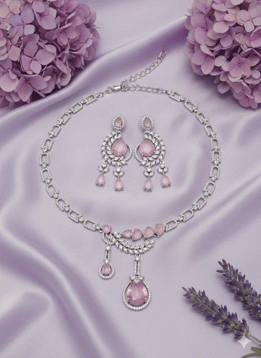 Intimate jewelry set featuring rose gold plated leaf motif necklace with cubic zirconia and matching earrings on lavender silk background