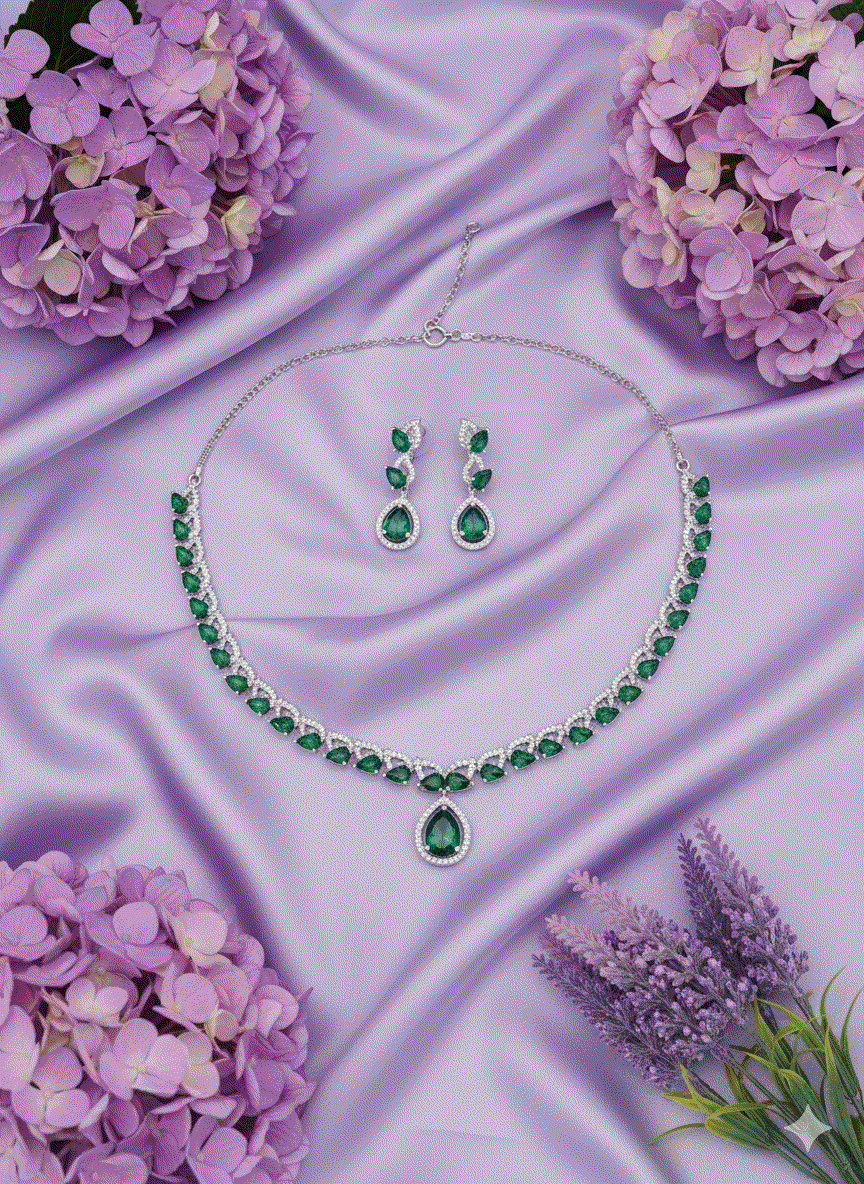 Pear-cut emerald green necklace and earrings set with rhodium plating on purple satin background