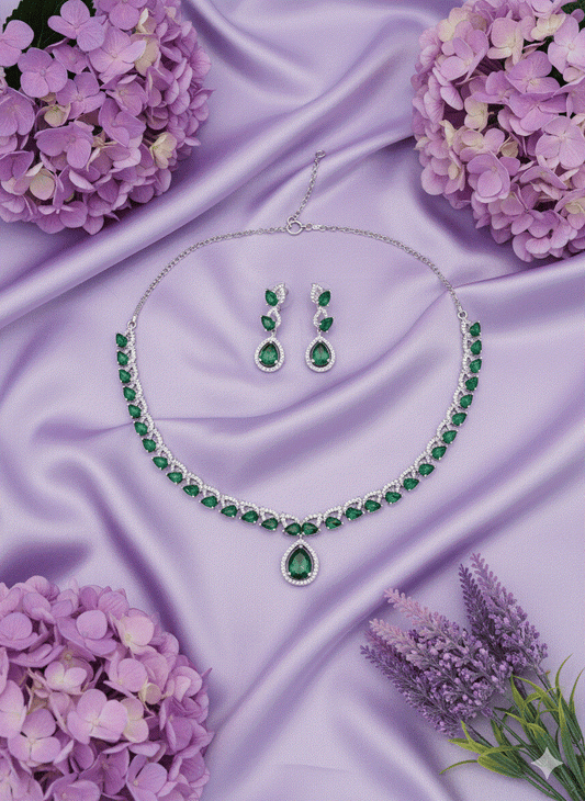 Pear-cut emerald green necklace and earrings set with rhodium plating on purple satin background