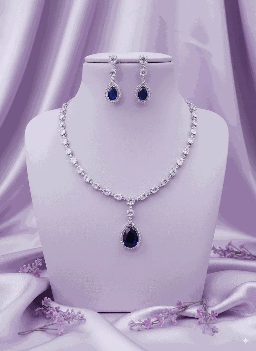Royal blue sapphire CZ diamond necklace and drop earrings set with silver-toned plating on purple fabric background