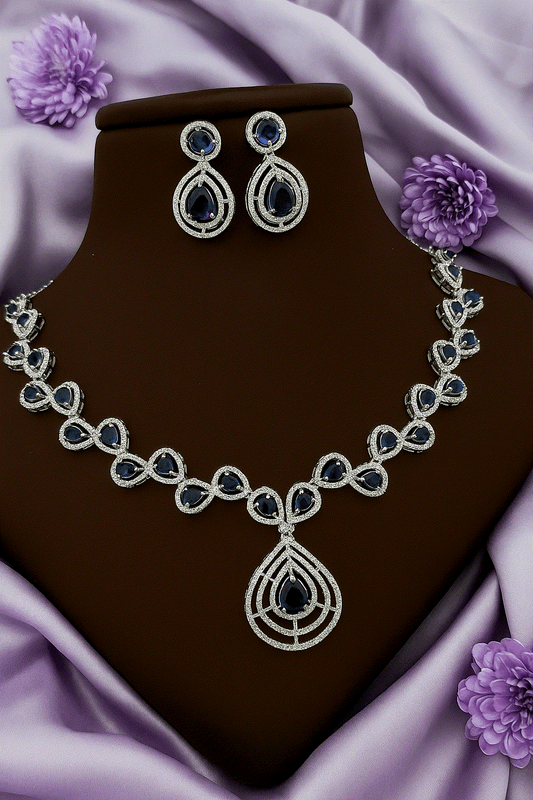 Luxury Deep Sapphire CZ diamond white gold tone bridal necklace and drop earrings set on purple fabric background