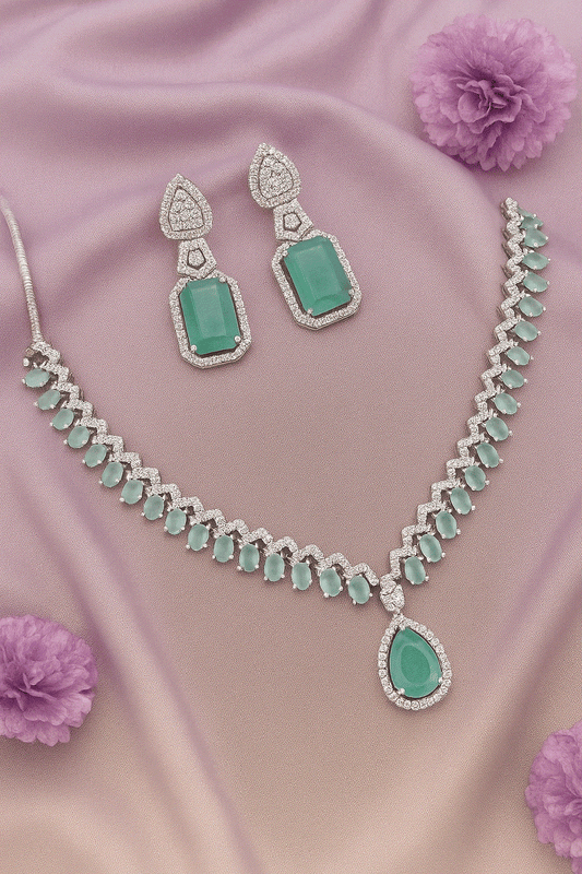 Luxury CZ Intimate Jewelry Set with mint green gemstones, rhodium-plated bridal necklace and emerald drop earrings on pink fabric background