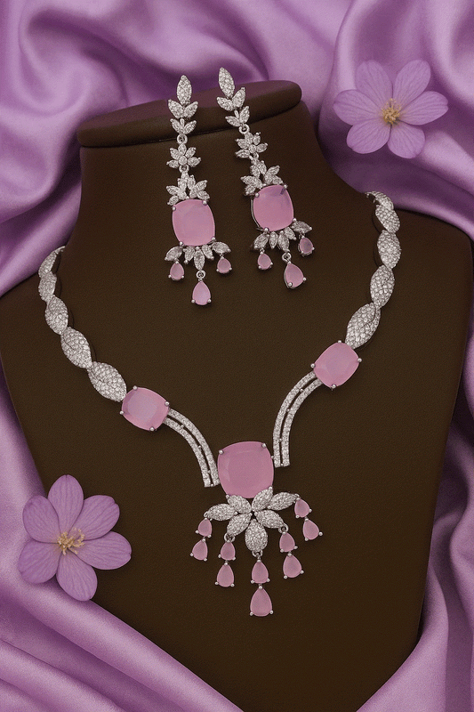 Elegant intimate jewelry set featuring pink CZ floral drop necklace and matching earrings with rhodium plating on purple satin background